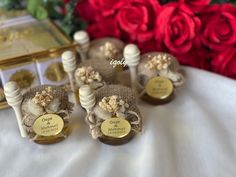 four small bottles are sitting on a table with red roses in the background and one is empty