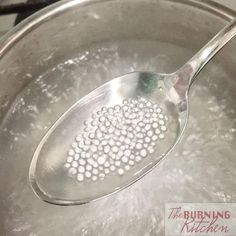 a metal spoon filled with water on top of a stove