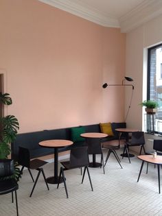 a room with tables and chairs in front of a pink wall that has been painted