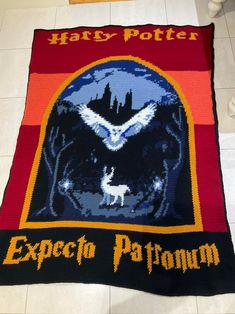 a harry potter blanket on the floor with an eagle and hogwarts crest over it