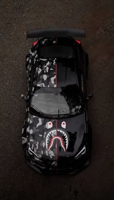 an overhead view of a black car with a shark on it's hood and red stripes