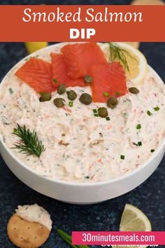 smoked salmon dip in a white bowl with crackers and lemons on the side