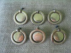 six different sized metal pendants sitting on top of a cloth