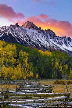 the mountains are covered in snow and trees with long wooden fence posts lined up against them