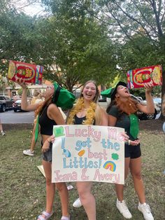 three young women holding up signs in the grass at a st patrick's day parade