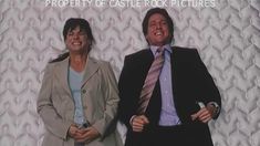 a man and woman standing next to each other in front of a white wall with the words property of castle rock pictures on it