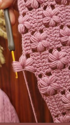 someone is crocheting the edge of a pink blanket