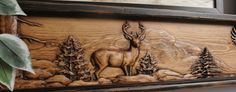 a wooden frame with deer and pine trees on it