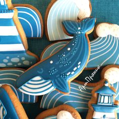 decorated cookies with blue and white designs in the shape of boats, lighthouses and waves