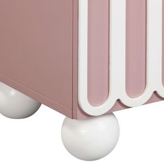 a close up of a pink and white cabinet with two balls on the bottom shelf