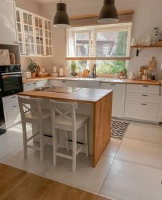 a kitchen with white cabinets and an island in the middle of the room, surrounded by wooden flooring