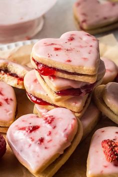 strawberry shortbread cookies with white frosting and raspberry fillings on a plate