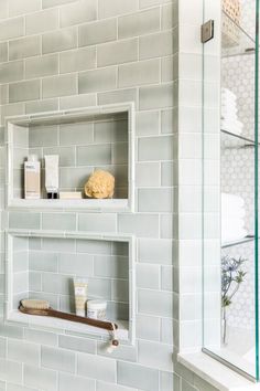 a white tiled bathroom with shelves on the wall