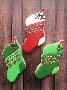 three decorated christmas cookies sitting on top of a wooden table