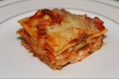 a white plate topped with lasagna covered in sauce