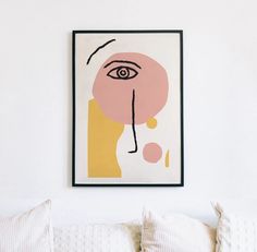 a painting hanging on the wall above a bed in a room with white walls and pillows