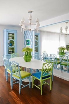 a dining room table with blue chairs and green vases on the top of it