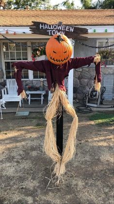 a scarecrow is hanging from a pole in front of a house with pumpkins on it