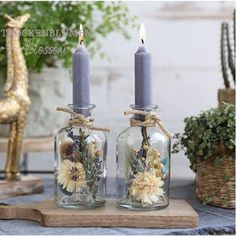 two glass jars with flowers are sitting on a table