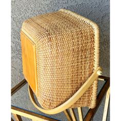 a wicker chair sitting on top of a glass table next to a gray wall