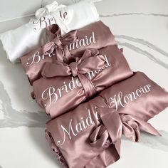 four bridesmaid sashes are laid out on a marble countertop with the names of their guests