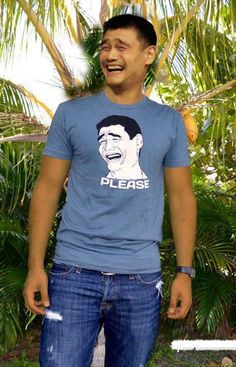 a man laughing and wearing a blue shirt with the word please on it in front of palm trees