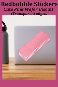 a pink sticker sitting on top of a laptop computer next to a black bottle