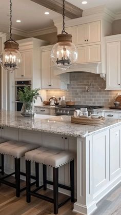 a large kitchen island with stools and lights hanging from it's ceiling over the counter