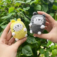 two small crocheted animals sitting next to each other in front of green leaves