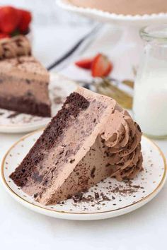 a slice of chocolate cake on a plate with strawberries and milk in the background