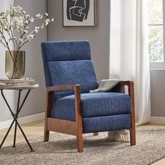 a blue recliner chair sitting on top of a rug in a living room next to a window