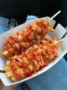 two skewers filled with ketchup and covered in sauce sitting on a plate