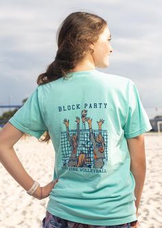 a girl standing on the beach with her back to the camera, wearing a t - shirt that says block party