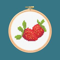 a cross stitch strawberry with green leaves on it