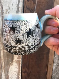 a hand holding a coffee mug with stars painted on it