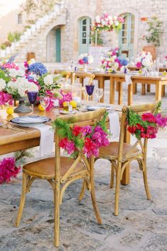 an outdoor dining area with tables and chairs covered in pink, white and blue flowers