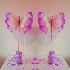 two vases filled with pink flowers on top of a white table covered in confetti