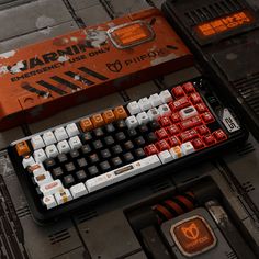 a computer keyboard sitting on top of a table next to a red and white box