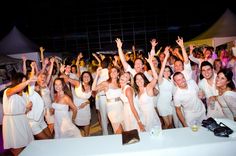 a large group of people standing next to each other in front of a white table