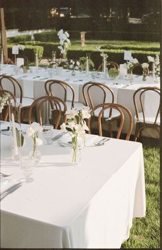 tables set up with white tablecloths and flowers in vases