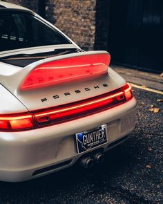 the rear end of a white porsche parked in front of a brick building