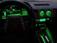 the interior of a car with green lights and gauges on it's dashboard