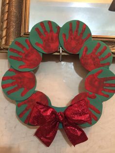 a handprinted wreath with red and green paint on it, sitting in front of a mirror