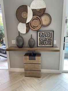 a table with some vases on top of it in front of a wall mounted art piece