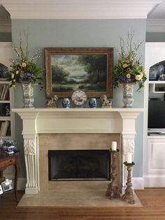 a living room with a fire place and vases on the mantle