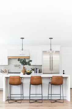 three stools sit at the center of a kitchen island