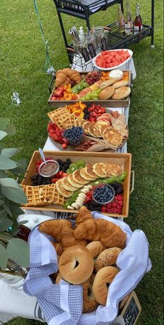 an assortment of pastries and fruit on display in baskets at a picnic table outdoors