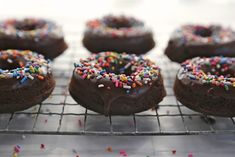 chocolate donuts with sprinkles on a cooling rack