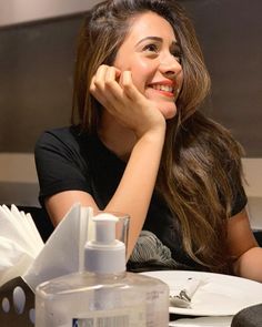 a woman is sitting at a table with her hand on her chin and looking off to the side