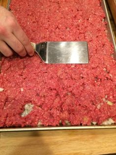 a person using a knife to cut up ground beef